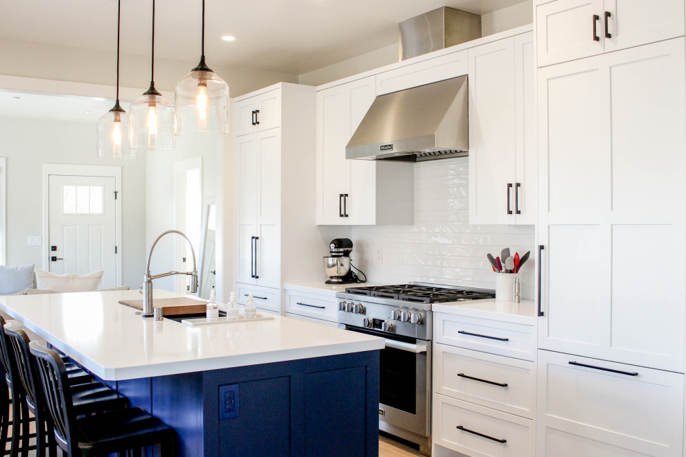 Example of a transitional beige floor kitchen design with shaker cabinets, white backsplash, subway tile backsplash, an island and white countertops