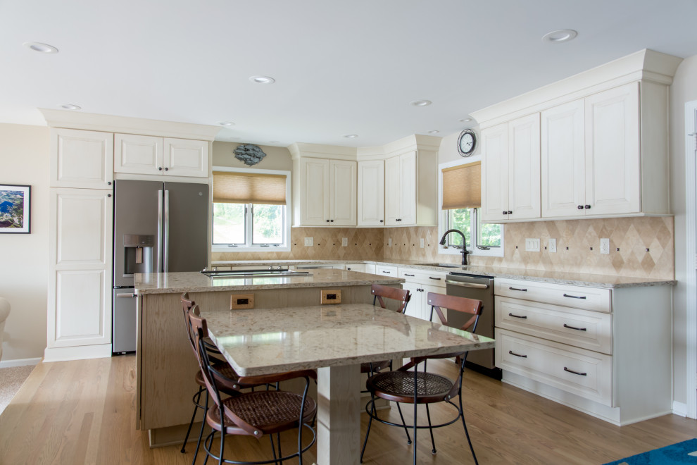 Example of a transitional l-shaped light wood floor kitchen design with an undermount sink, raised-panel cabinets, white cabinets, beige backsplash, stainless steel appliances, an island and beige countertops