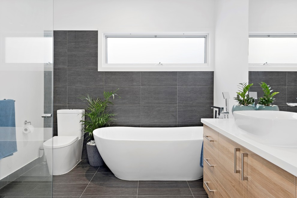 Design ideas for a beach style 3/4 bathroom in Melbourne with flat-panel cabinets, beige cabinets, a freestanding tub, a corner shower, a one-piece toilet, gray tile, white walls, a vessel sink, grey floor, a hinged shower door and white benchtops.