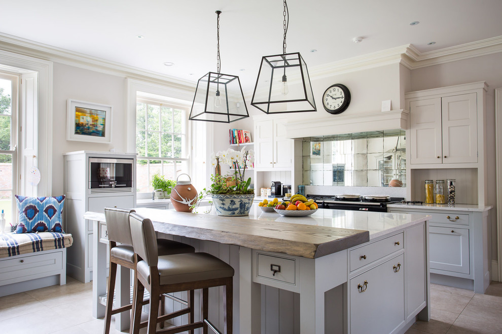 Photo of a country l-shaped open plan kitchen in Other with shaker cabinets, white cabinets, metallic splashback, mirror splashback, black appliances, with island and beige floor.