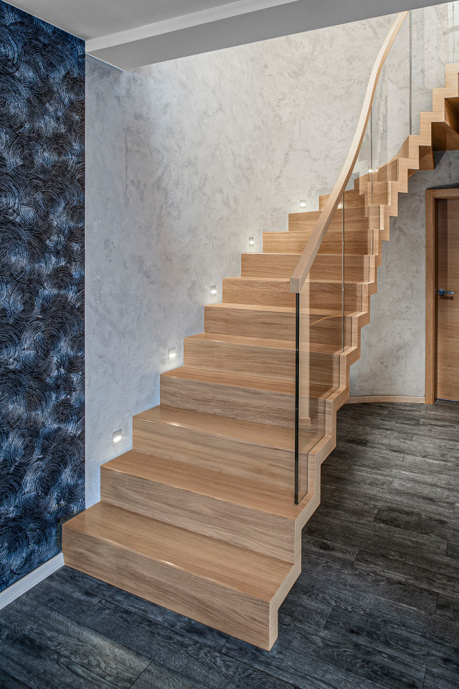 Contemporary wood curved staircase in Hamburg with wood risers and glass railing.