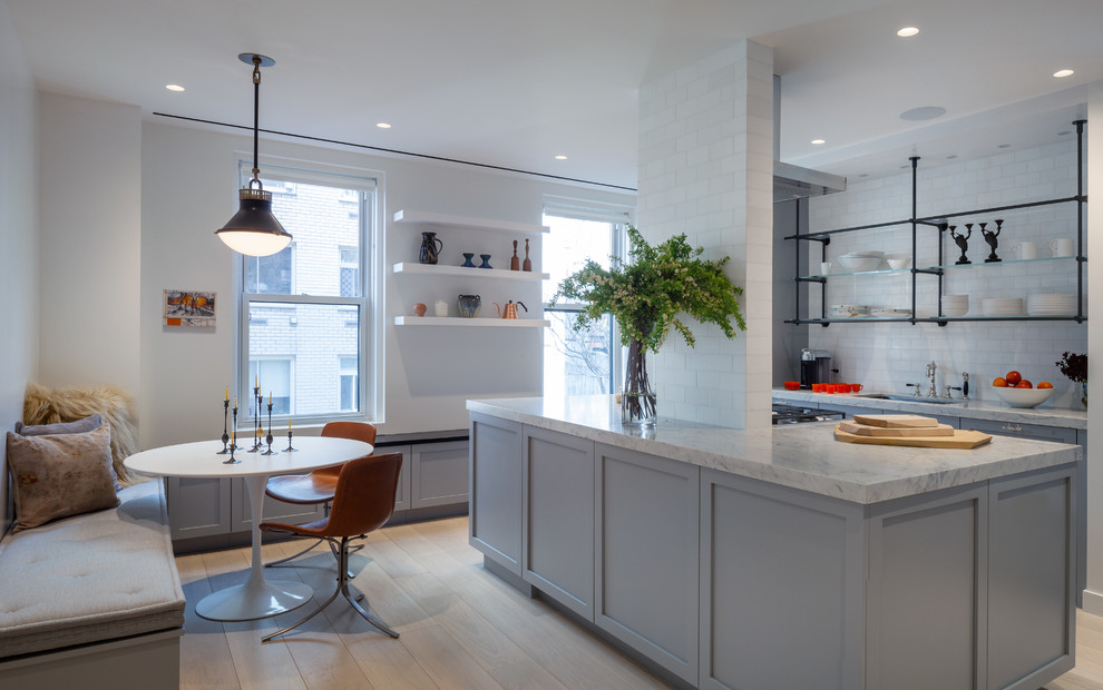 Design ideas for a large transitional u-shaped eat-in kitchen in New York with an undermount sink, shaker cabinets, grey cabinets, white splashback, subway tile splashback, light hardwood floors, with island, beige floor, white benchtop, marble benchtops and stainless steel appliances.