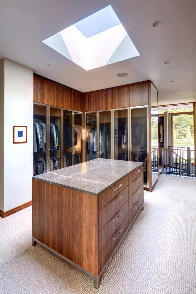 Photo of a contemporary walk-in wardrobe in Detroit with glass-front cabinets, medium wood cabinets, carpet and grey floor.