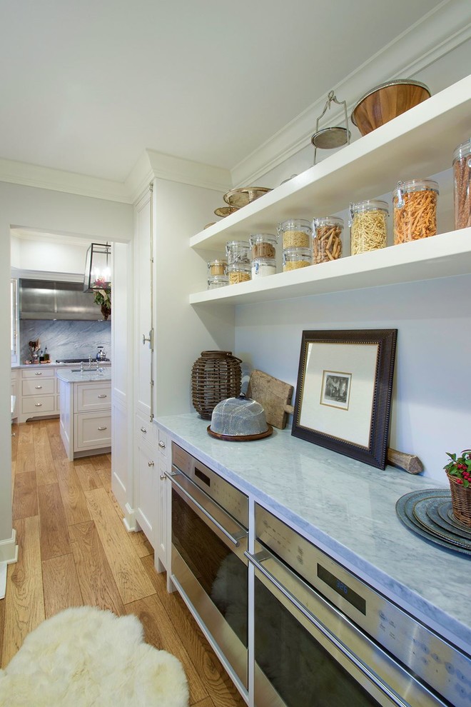 Open concept kitchen - large transitional l-shaped medium tone wood floor open concept kitchen idea in Austin with a farmhouse sink, shaker cabinets, white cabinets, marble countertops, multicolored backsplash, stone slab backsplash, stainless steel appliances and an island