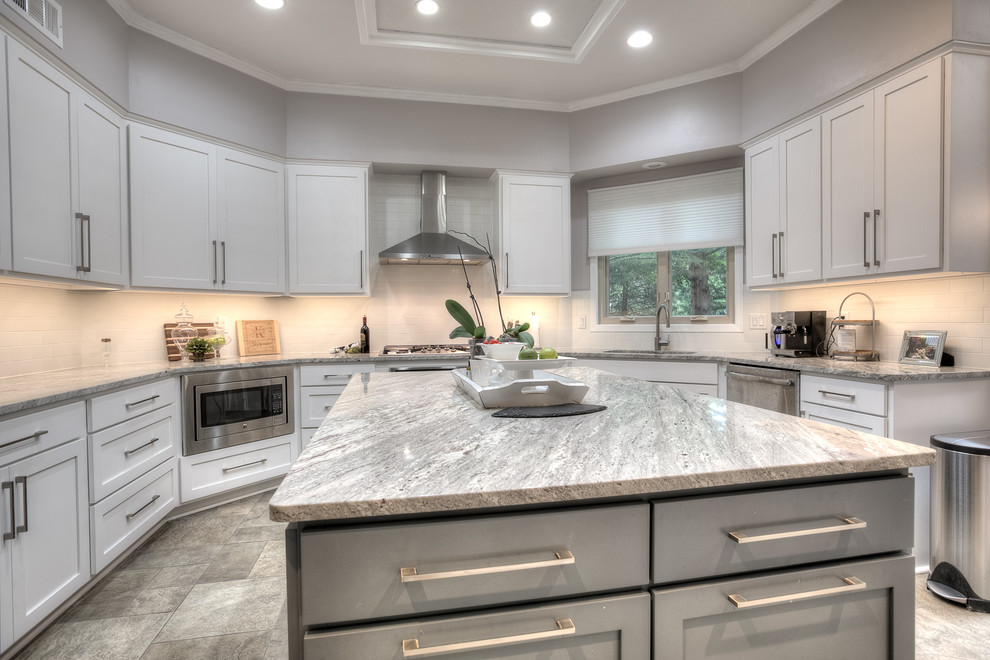 This is an example of a mid-sized transitional u-shaped separate kitchen in Kansas City with an undermount sink, shaker cabinets, white cabinets, granite benchtops, stainless steel appliances, with island and brown floor.