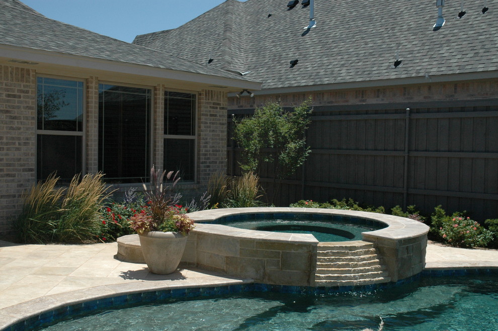 Design ideas for a large country backyard custom-shaped natural pool in Austin with natural stone pavers and a hot tub.