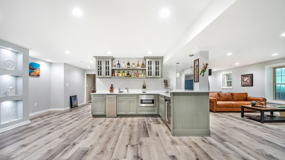 This is an example of a medium sized classic l-shaped wet bar in DC Metro with a submerged sink, raised-panel cabinets, grey cabinets, granite worktops, white splashback, metro tiled splashback, vinyl flooring, grey floors and white worktops.