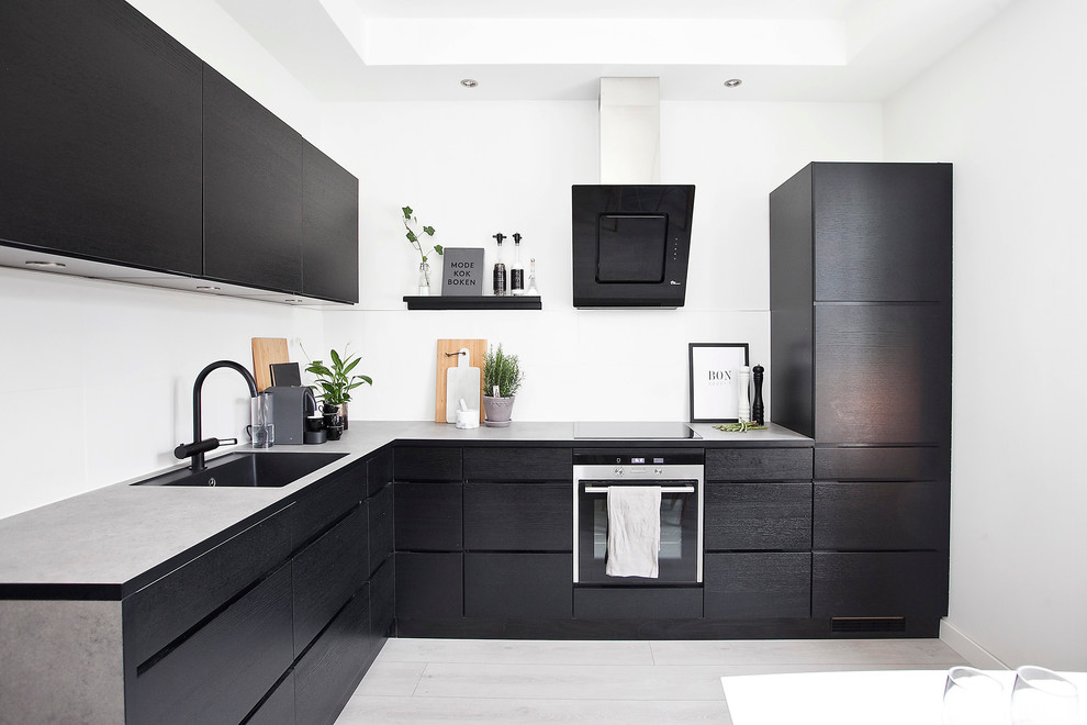 Inspiration for a large scandinavian l-shaped separate kitchen in Malmo with a single-bowl sink, flat-panel cabinets, black cabinets, concrete benchtops, black appliances, limestone floors and no island.