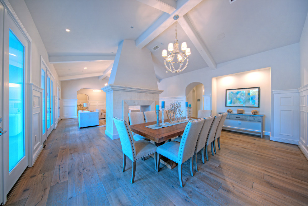 This is an example of a large mediterranean open plan dining in Phoenix with grey walls, medium hardwood floors and a two-sided fireplace.
