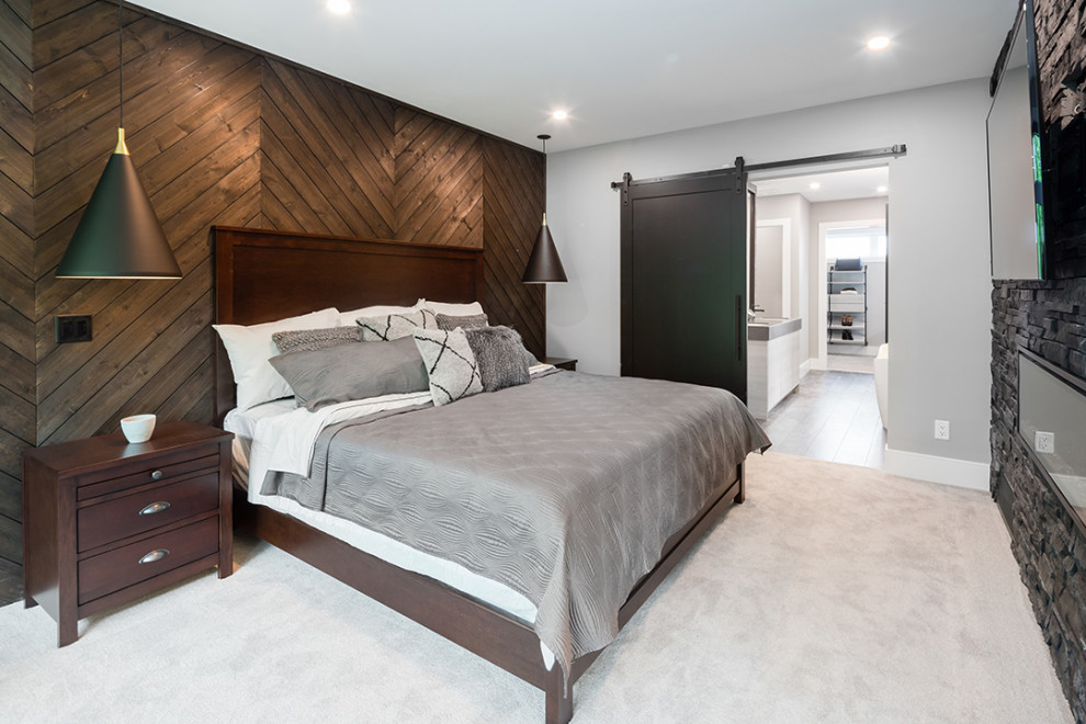This is an example of a beach style master bedroom in Vancouver with multi-coloured walls, carpet, a standard fireplace, a stone fireplace surround, grey floor and panelled walls.