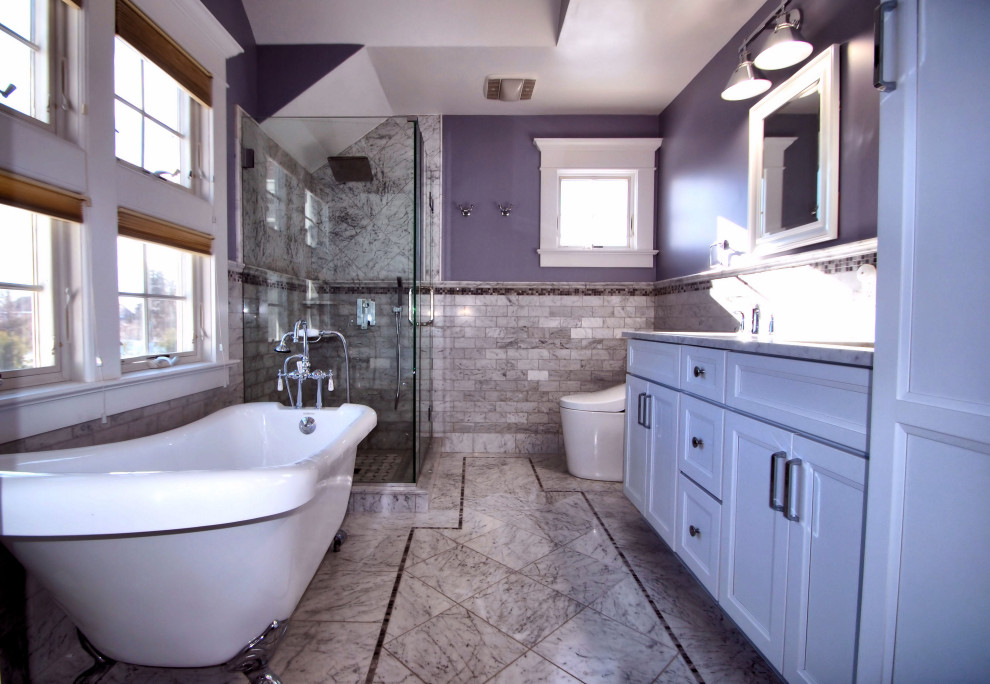 Cette image montre une salle de bain principale traditionnelle de taille moyenne avec un placard avec porte à panneau encastré, des portes de placard blanches, une baignoire sur pieds, une douche d'angle, un bidet, un carrelage blanc, du carrelage en marbre, un mur violet, un sol en marbre, un lavabo encastré, un plan de toilette en quartz modifié, un sol blanc, une cabine de douche à porte battante, un plan de toilette blanc, meuble double vasque, meuble-lavabo encastré et un plafond voûté.