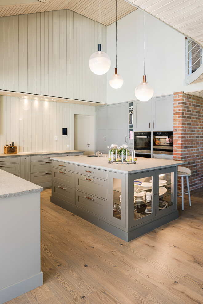 Design ideas for a scandinavian u-shaped open plan kitchen in Other with shaker cabinets, beige cabinets, beige splashback, timber splashback, black appliances, light hardwood floors, with island and beige floor.