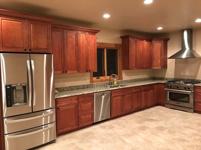 Example of a mid-sized mountain style u-shaped porcelain tile and gray floor open concept kitchen design in Denver with an undermount sink, raised-panel cabinets, medium tone wood cabinets, granite countertops, stainless steel appliances and no island