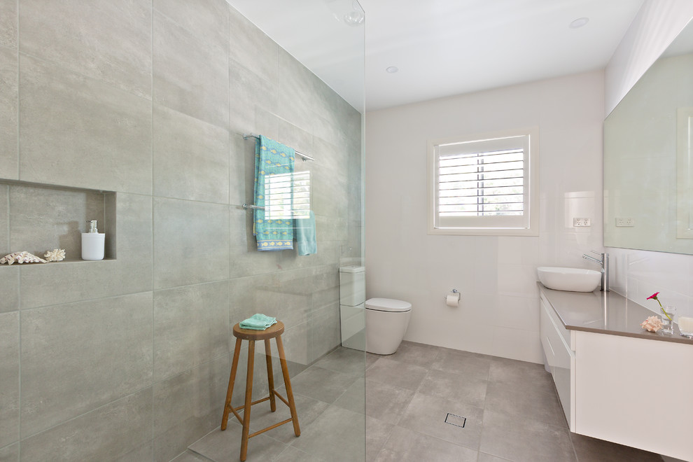 Inspiration for a beach style 3/4 bathroom in Sydney with flat-panel cabinets, white cabinets, a corner shower, a one-piece toilet, gray tile, cement tile, white walls, concrete floors, a vessel sink, grey floor, an open shower and brown benchtops.