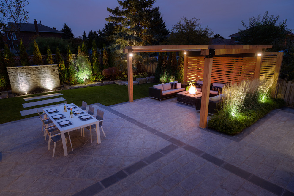 Photo of a modern backyard patio in Toronto with a fire feature and a pergola.