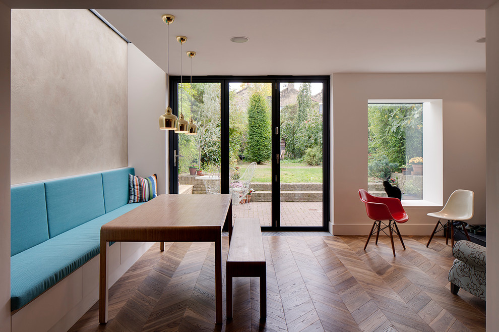 Photo of a contemporary open plan dining in London with white walls and medium hardwood floors.