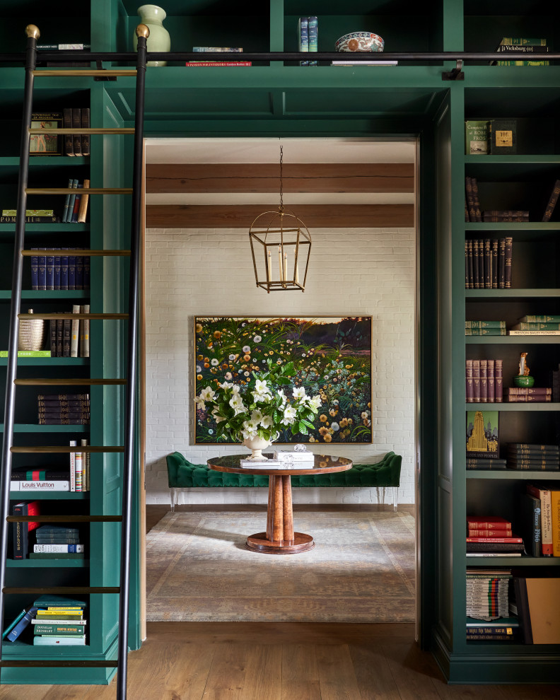Inredning av ett klassiskt stort arbetsrum, med ett bibliotek, gröna väggar, mellanmörkt trägolv, en standard öppen spis, ett fristående skrivbord och brunt golv