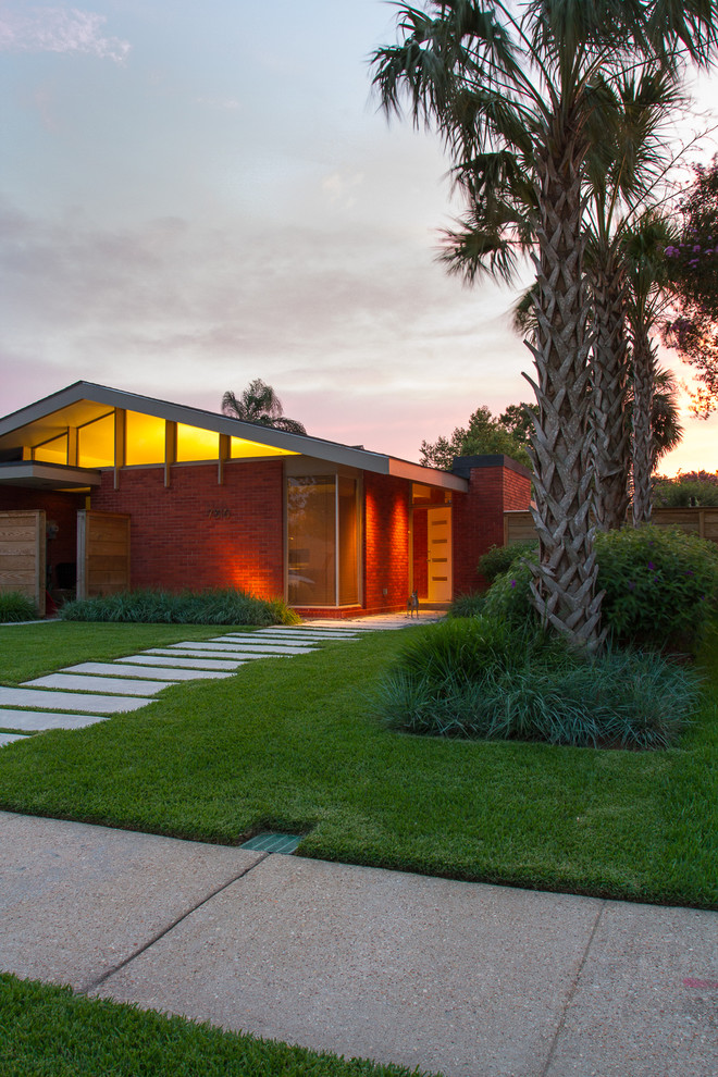 This is an example of a midcentury one-storey brick exterior in New Orleans with a gable roof.