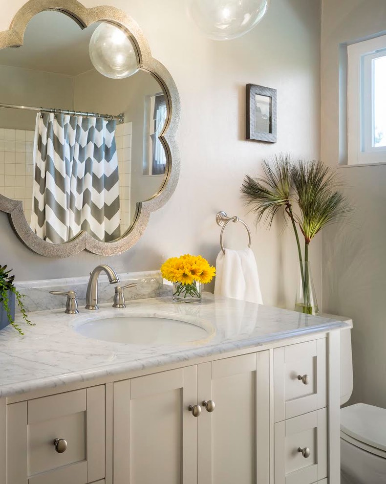 Inspiration for a mid-sized transitional kids bathroom in San Francisco with shaker cabinets, white cabinets, an alcove tub, a shower/bathtub combo, a one-piece toilet, white tile, grey walls, an undermount sink, marble benchtops, a shower curtain, light hardwood floors and brown floor.