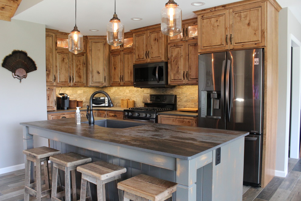 Mid-sized mountain style l-shaped ceramic tile and multicolored floor eat-in kitchen photo in Philadelphia with an undermount sink, raised-panel cabinets, medium tone wood cabinets, stone tile backsplash, black appliances, an island, stainless steel countertops and beige backsplash