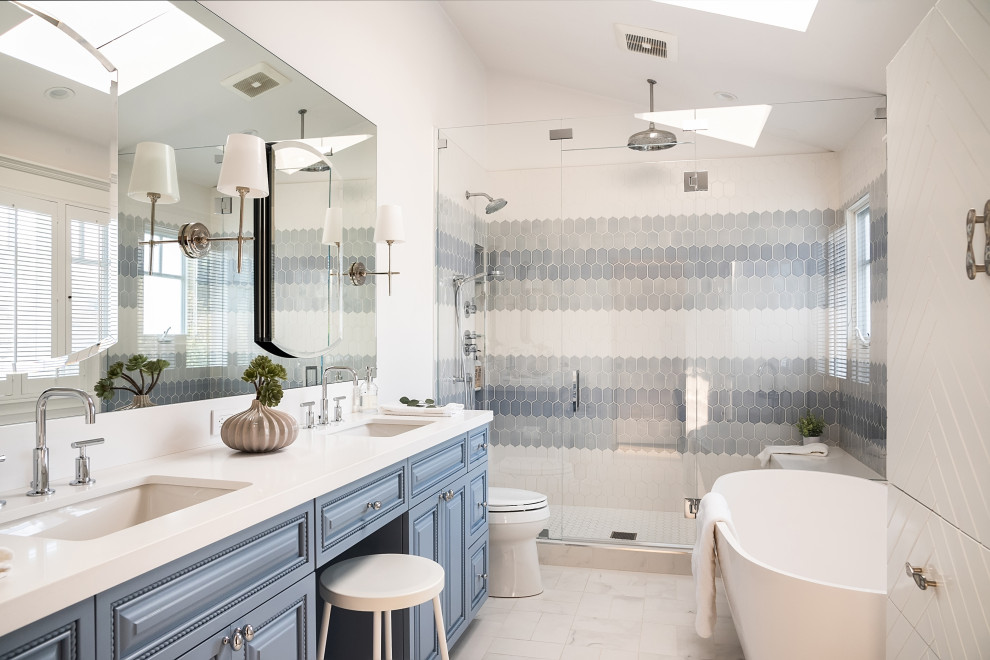 Photo of a mid-sized beach style master bathroom in Los Angeles with blue cabinets, a freestanding tub, a one-piece toilet, yellow tile, ceramic tile, white walls, an undermount sink, white floor, a hinged shower door, white benchtops, a shower seat, a double vanity, a built-in vanity, vaulted and raised-panel cabinets.