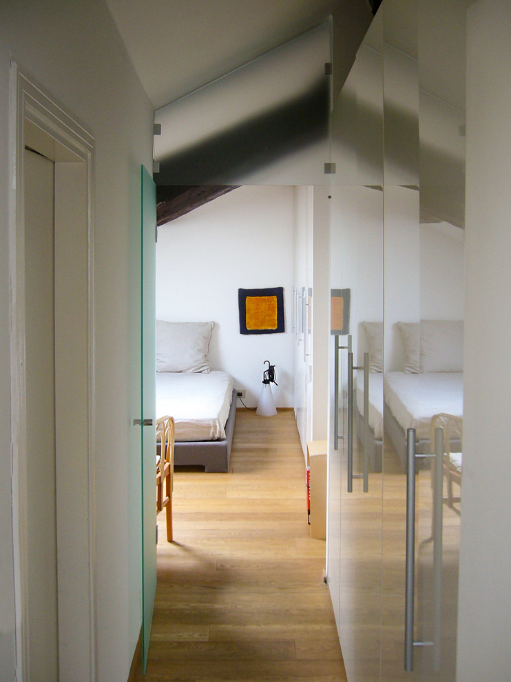 This is an example of a small contemporary hallway in Milan with white walls, painted wood floors and brown floor.