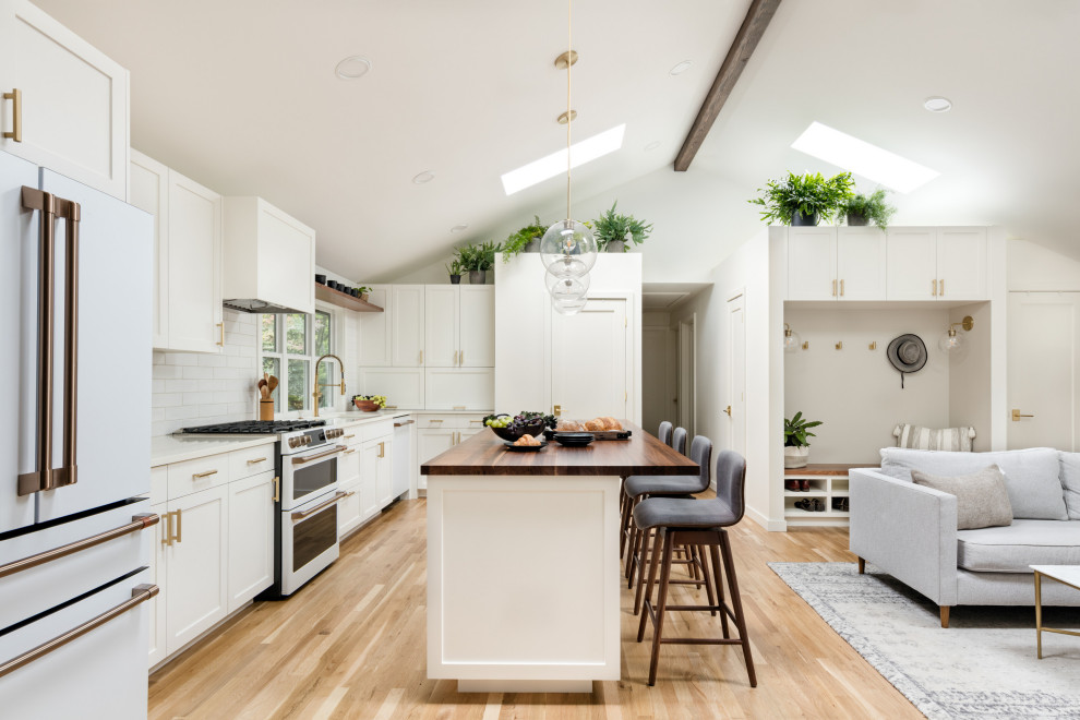 Eat-in kitchen - mid-sized scandinavian l-shaped light wood floor and vaulted ceiling eat-in kitchen idea in Seattle with an undermount sink, recessed-panel cabinets, white cabinets, quartz countertops, white backsplash, subway tile backsplash, white appliances, an island and white countertops