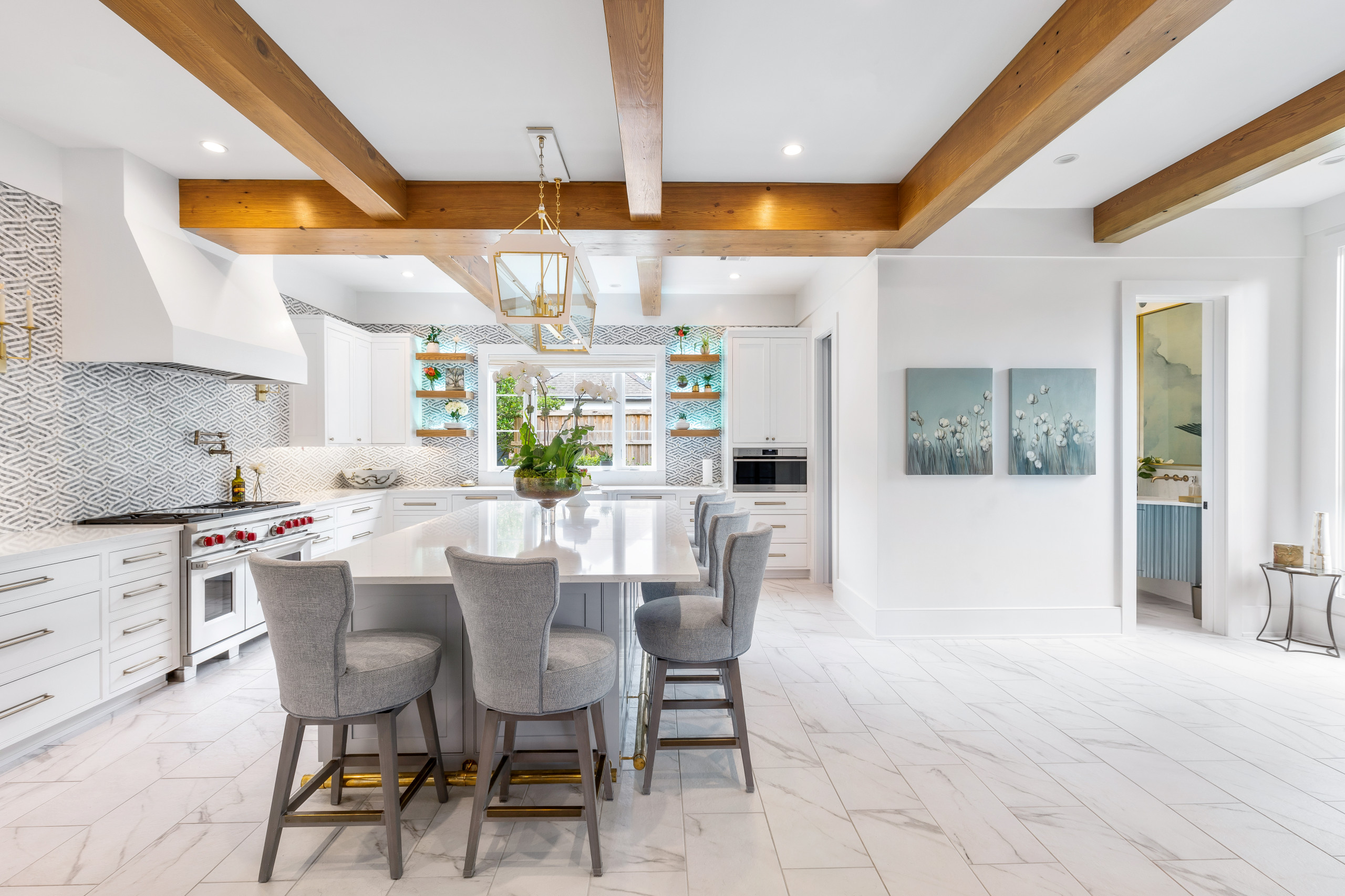 Beautiful open spacing floor plan for the kitchen, the white walls compliment the marble tile flooring. Engineered beams and floating shelves with blue accents in the  backsplash and decor.