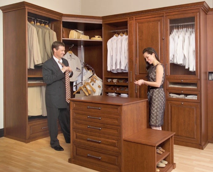This is an example of a large transitional women's walk-in wardrobe in Montreal with recessed-panel cabinets, medium wood cabinets and light hardwood floors.