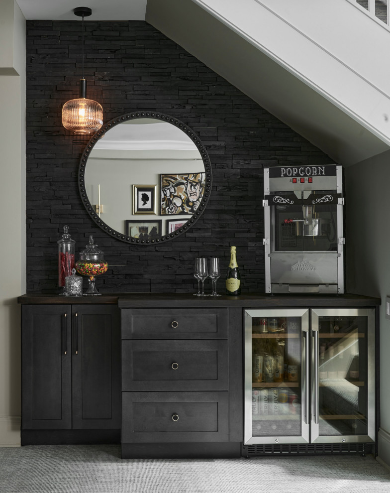 Inspiration for a large retro single-wall dry bar in Chicago with recessed-panel cabinets, black cabinets, black splashback, carpet, grey floors and black worktops.
