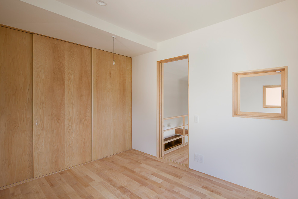 Photo of a mid-sized gender-neutral kids' room in Tokyo with white walls, light hardwood floors, wallpaper and wallpaper.