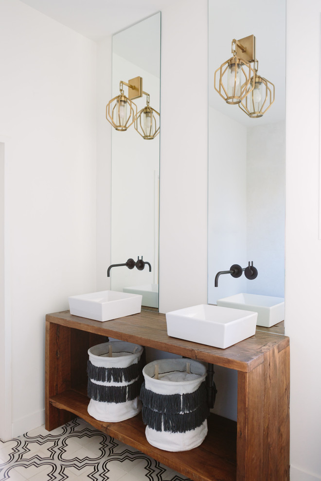 This is an example of a beach style bathroom in Nashville with open cabinets, medium wood cabinets, white walls, a vessel sink, wood benchtops and multi-coloured floor.
