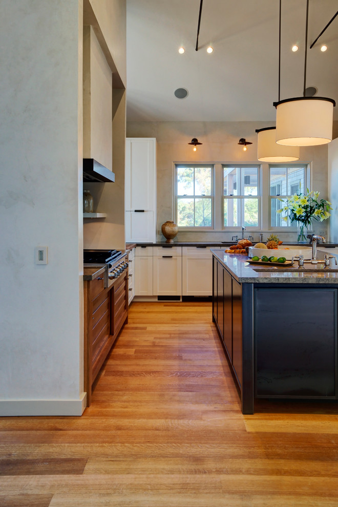 Photo of a mid-sized transitional u-shaped eat-in kitchen in Boston with white cabinets, an undermount sink, beaded inset cabinets, multi-coloured splashback, glass tile splashback, stainless steel appliances, light hardwood floors, with island and granite benchtops.