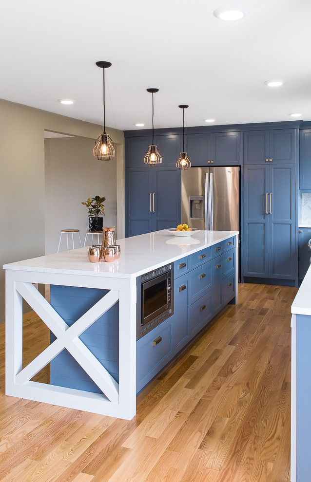 Enclosed kitchen - large transitional l-shaped medium tone wood floor and brown floor enclosed kitchen idea with a double-bowl sink, recessed-panel cabinets, blue cabinets, marble countertops, white backsplash, marble backsplash, stainless steel appliances and an island