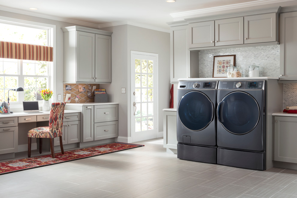 Design ideas for a mid-sized traditional single-wall utility room in New York with grey cabinets, solid surface benchtops, grey walls, slate floors, a side-by-side washer and dryer and recessed-panel cabinets.