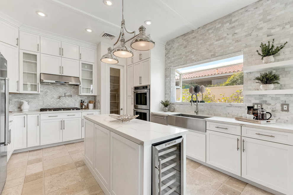 Design ideas for a mid-sized transitional eat-in kitchen in Las Vegas with a farmhouse sink, shaker cabinets, white cabinets, limestone benchtops, grey splashback, marble splashback, stainless steel appliances, limestone floors, with island and beige floor.