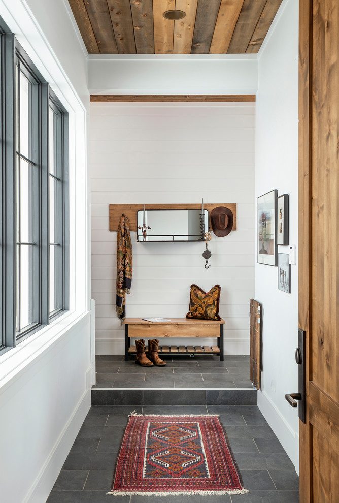 This is an example of a country entry hall in Salt Lake City with white walls, a single front door, a medium wood front door and grey floor.