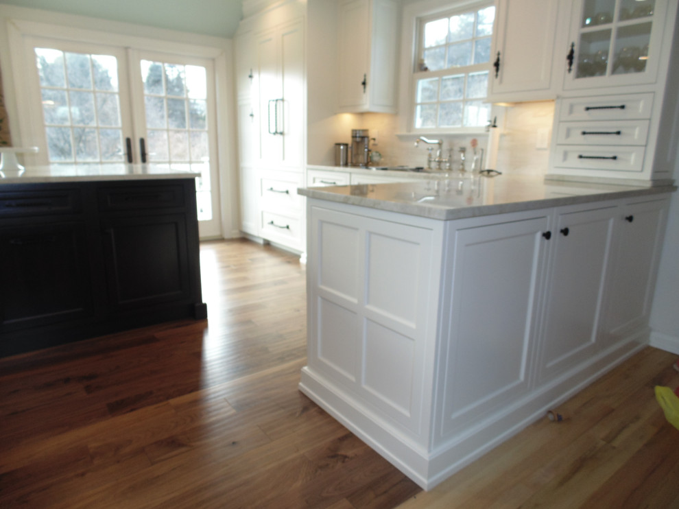 Large transitional u-shaped medium tone wood floor and brown floor eat-in kitchen photo with an undermount sink, recessed-panel cabinets, white cabinets, quartzite countertops, beige backsplash, subway tile backsplash, stainless steel appliances, an island and beige countertops