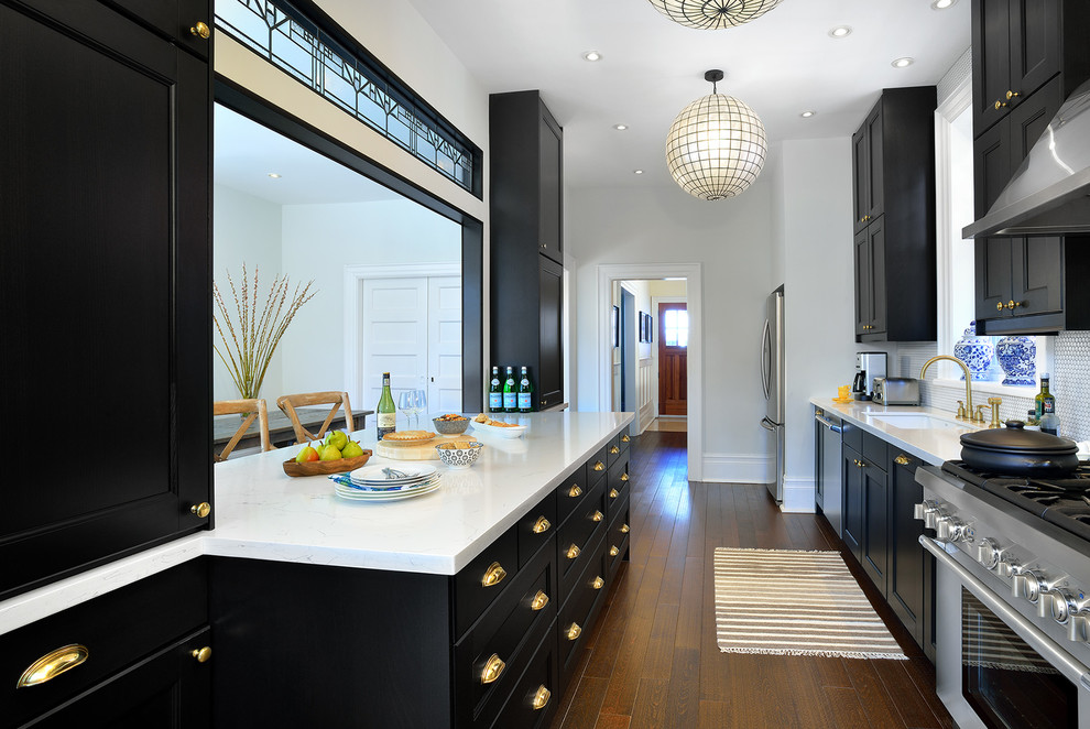 This is an example of a mid-sized traditional galley eat-in kitchen in Toronto with dark wood cabinets, quartzite benchtops, white splashback, mosaic tile splashback, stainless steel appliances, with island, a single-bowl sink, recessed-panel cabinets, dark hardwood floors and brown floor.