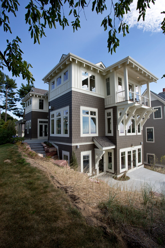 This is an example of a large beach style three-storey grey exterior in Grand Rapids with concrete fiberboard siding and a gable roof.