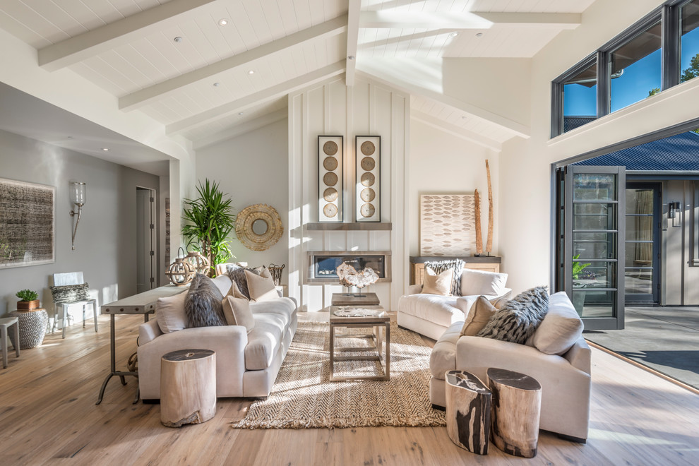 This is an example of a large country formal open concept living room in San Francisco with white walls, light hardwood floors, a ribbon fireplace, a metal fireplace surround, no tv and beige floor.