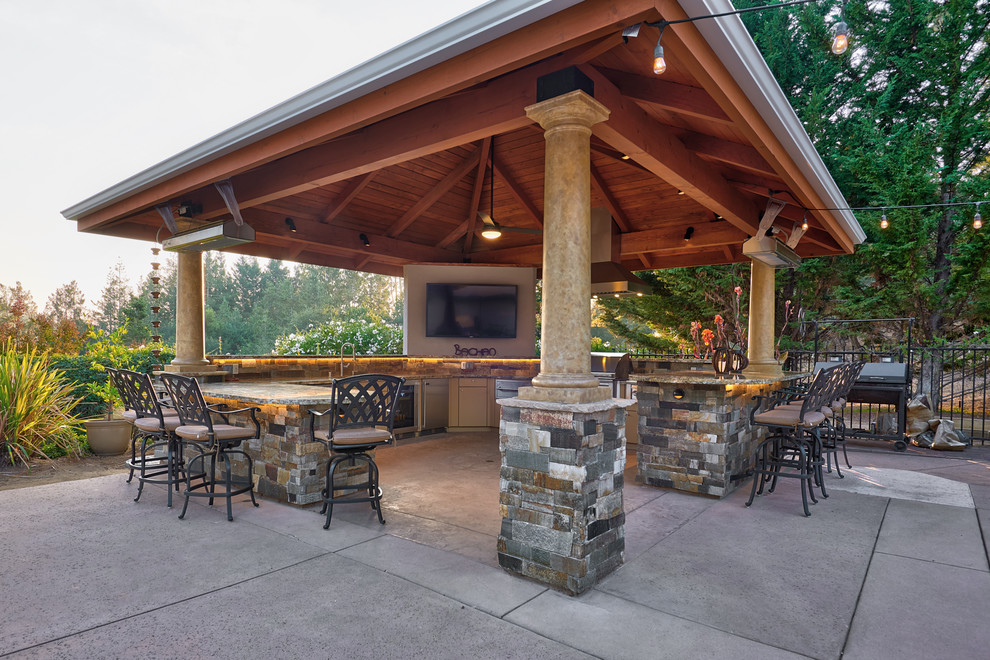 This is an example of a large transitional backyard patio in Other with an outdoor kitchen, stamped concrete and a gazebo/cabana.