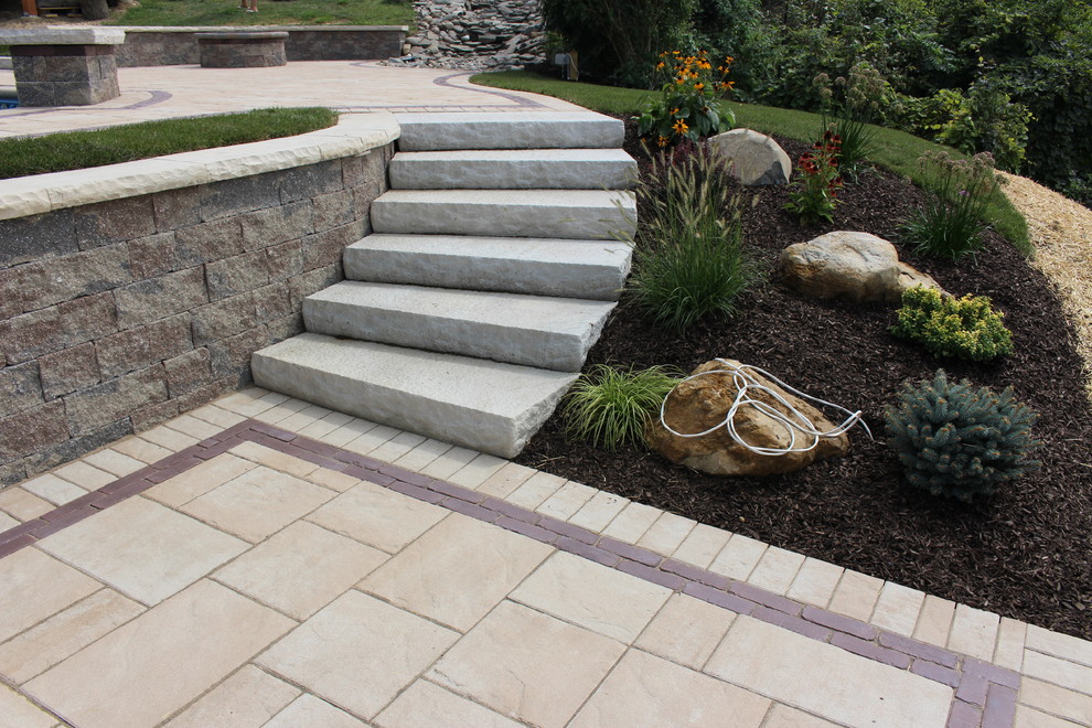 This is an example of a small traditional backyard full sun formal garden for summer in New York with a retaining wall and natural stone pavers.