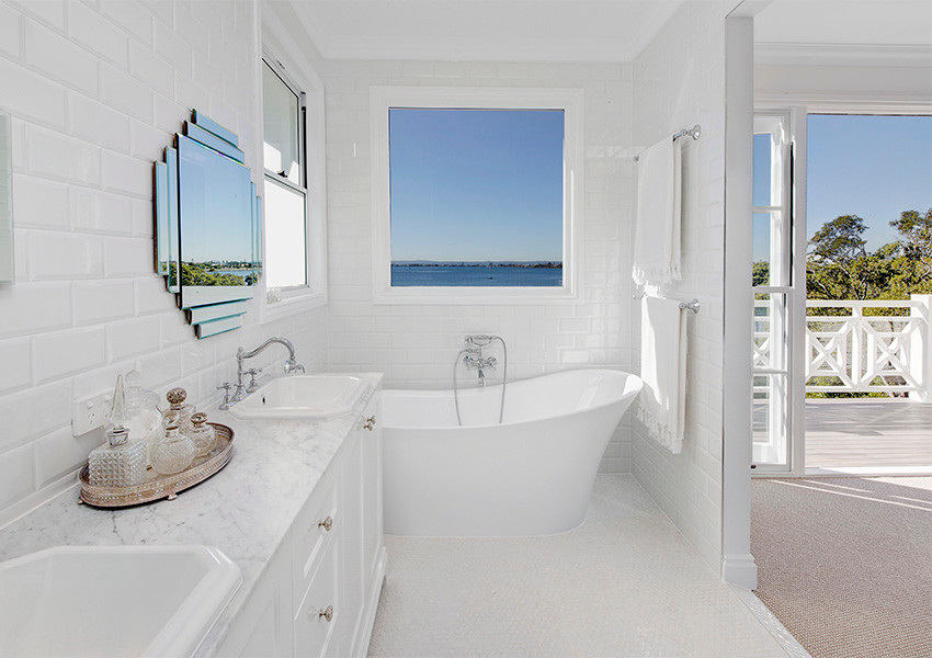 This is an example of a mid-sized traditional master bathroom in Brisbane with a drop-in sink, shaker cabinets, white cabinets, marble benchtops, a freestanding tub, an open shower, a one-piece toilet, white tile, ceramic tile, white walls and mosaic tile floors.