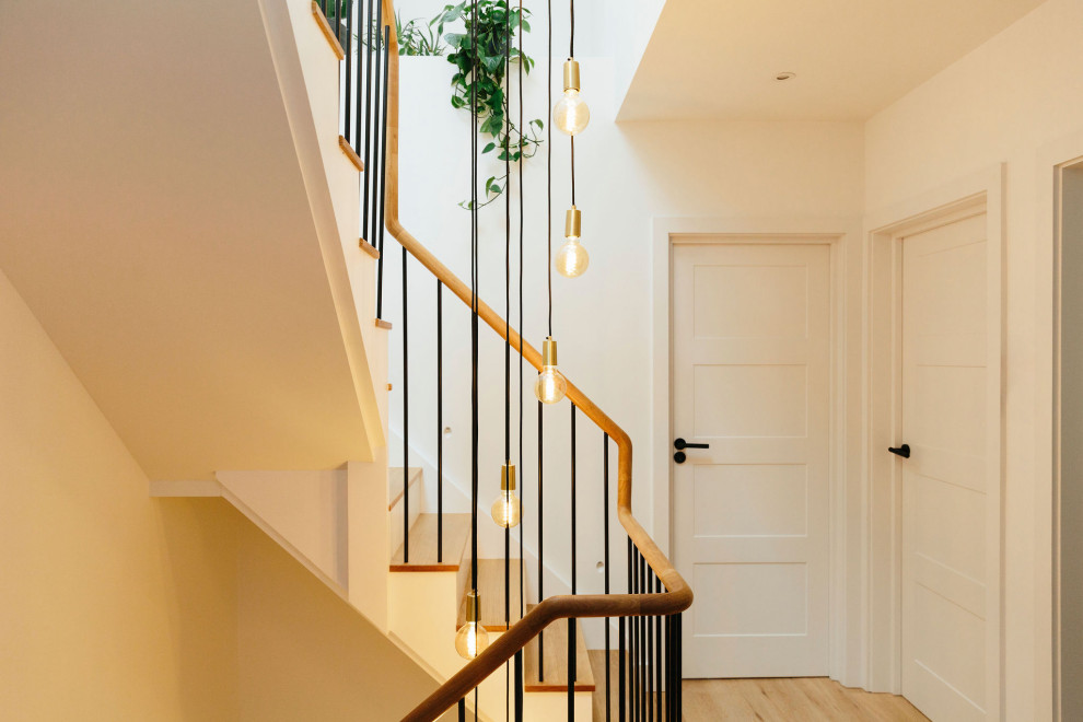 This is an example of a mid-sized transitional hallway in London with white walls, medium hardwood floors and beige floor.