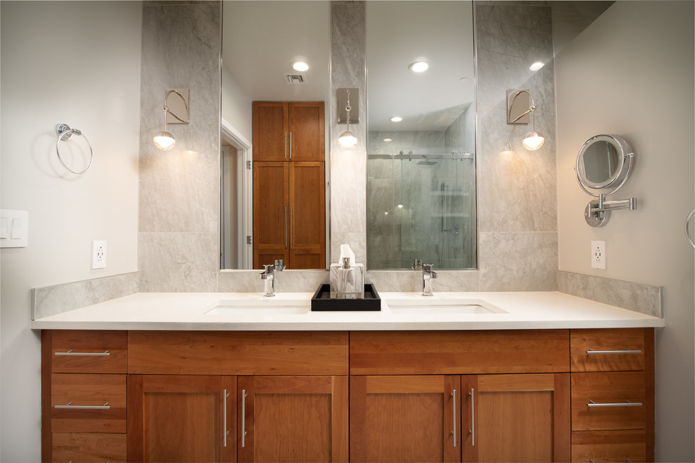 Design ideas for a mid-sized modern master bathroom in Baltimore with shaker cabinets, medium wood cabinets, an alcove shower, a bidet, gray tile, ceramic tile, beige walls, ceramic floors, an undermount sink, engineered quartz benchtops, multi-coloured floor, a sliding shower screen and white benchtops.