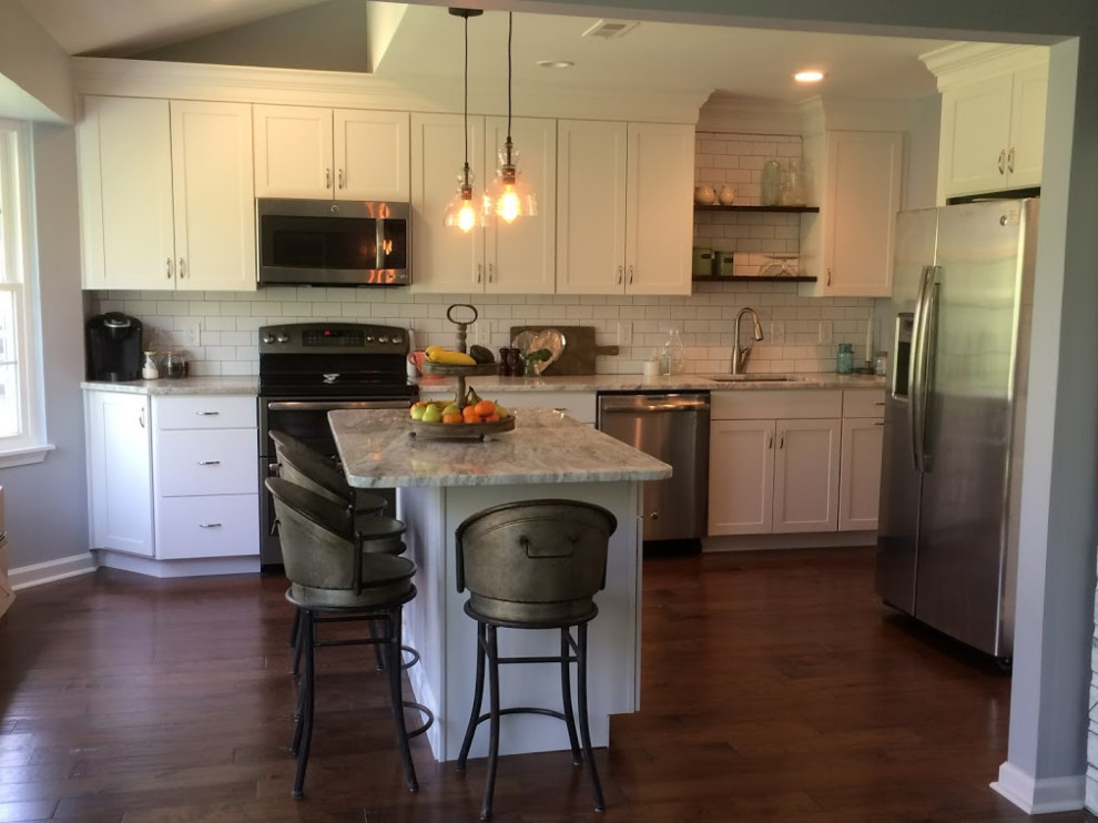 Mid-sized transitional single-wall eat-in kitchen in Philadelphia with an undermount sink, shaker cabinets, white cabinets, granite benchtops, white splashback, subway tile splashback, stainless steel appliances, dark hardwood floors, with island, brown floor and grey benchtop.