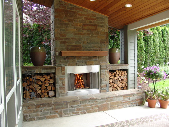 Outdoor kitchen and outdoor fireplace custom built and designed with natural stone under their covered porch. Allows for enjoyment and useage year around.
