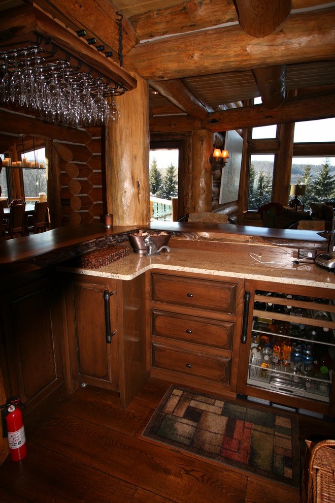 Seated home bar - huge rustic l-shaped medium tone wood floor seated home bar idea with raised-panel cabinets, distressed cabinets and wood countertops