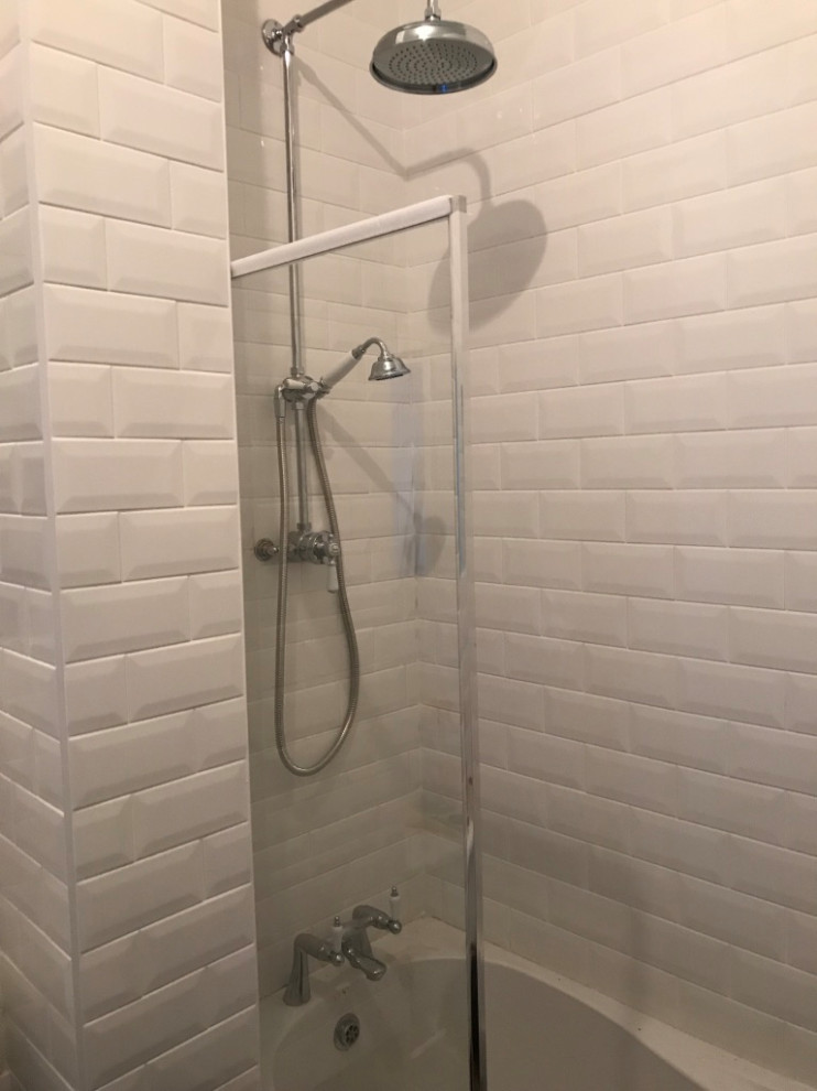 This is an example of a mid-sized traditional kids bathroom in London with a freestanding tub, a curbless shower, a one-piece toilet, white tile, ceramic tile, white walls, ceramic floors, a pedestal sink, white floor, a hinged shower door and a single vanity.